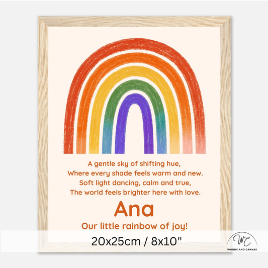 Personalized framed children's art print featuring a colorful rainbow and a poem, with the name 'Ana' and the text 'Our little rainbow of joy!' shown on a light wood frame against a white background.