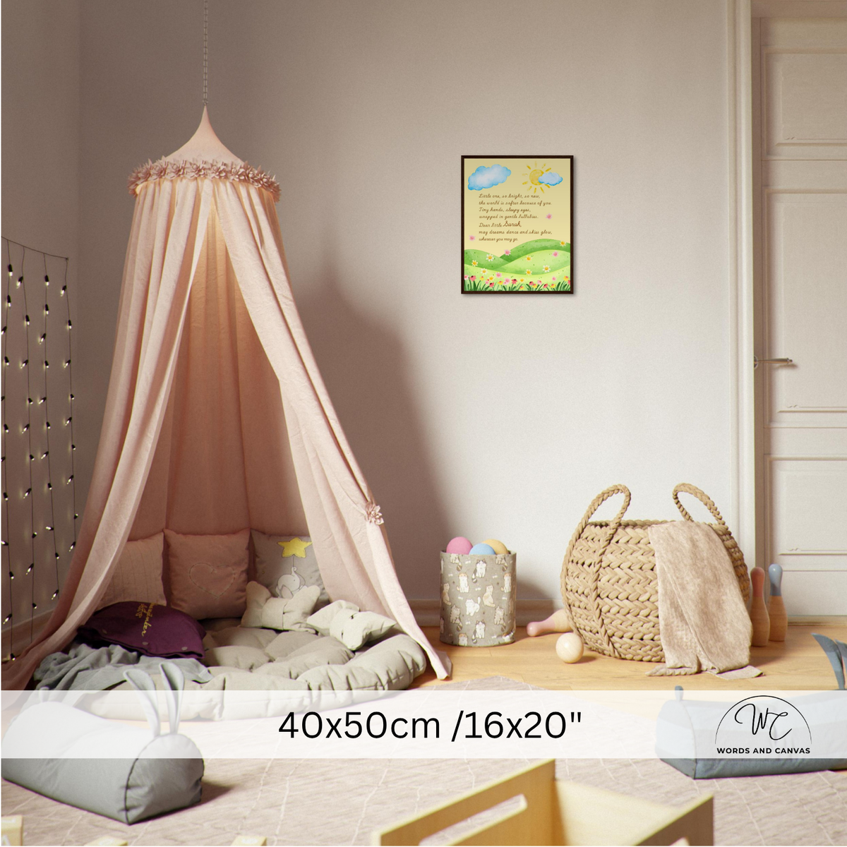 A children's bedroom corner with a large blush pink canopy bed hanging over a floor cushion and pillows. A small framed landscape print hangs on the wall above, and a woven basket with a blanket sits on the floor nearby.