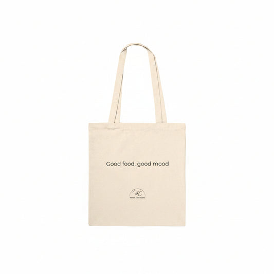 A natural canvas tote bag with two shoulder straps, featuring the printed text 'Good food, good mood' and a small circular logo near the bottom, shown against a plain white background.