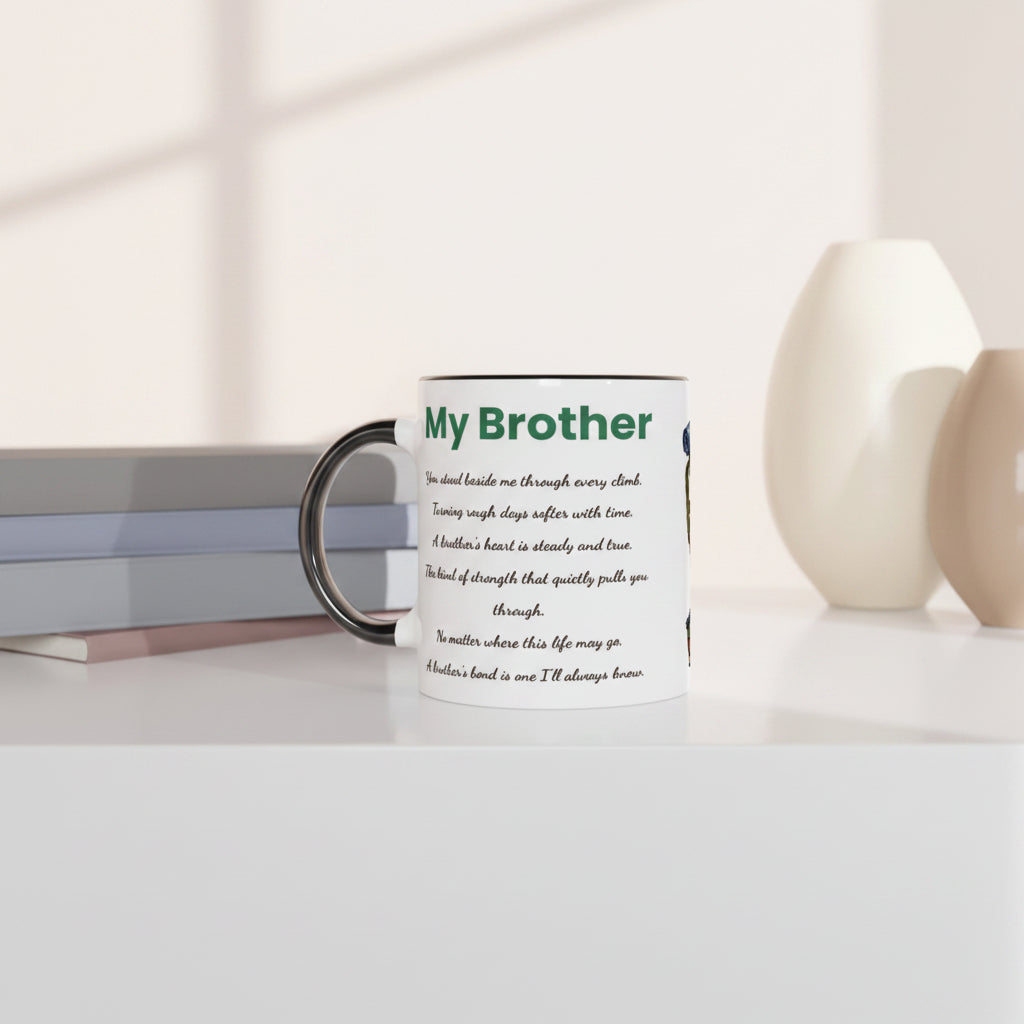 A white ceramic mug with a black handle and rim, printed with a green and black 'My Brother' message, styled on a white surface with books and ceramic vases in the background.