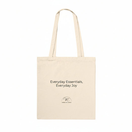 A natural canvas tote bag with black printed text reading 'Everyday Essentials, Everyday Joy' and a small circular logo below, shown on a plain white background.