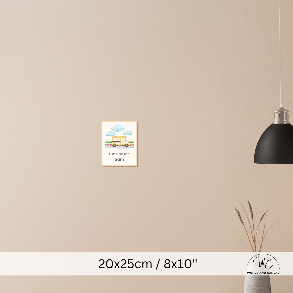 A small framed wall art print hangs on a beige wall in a styled interior. The print shows a colourful illustration of a house under blue clouds with the text 'Fun ride for Sam'.