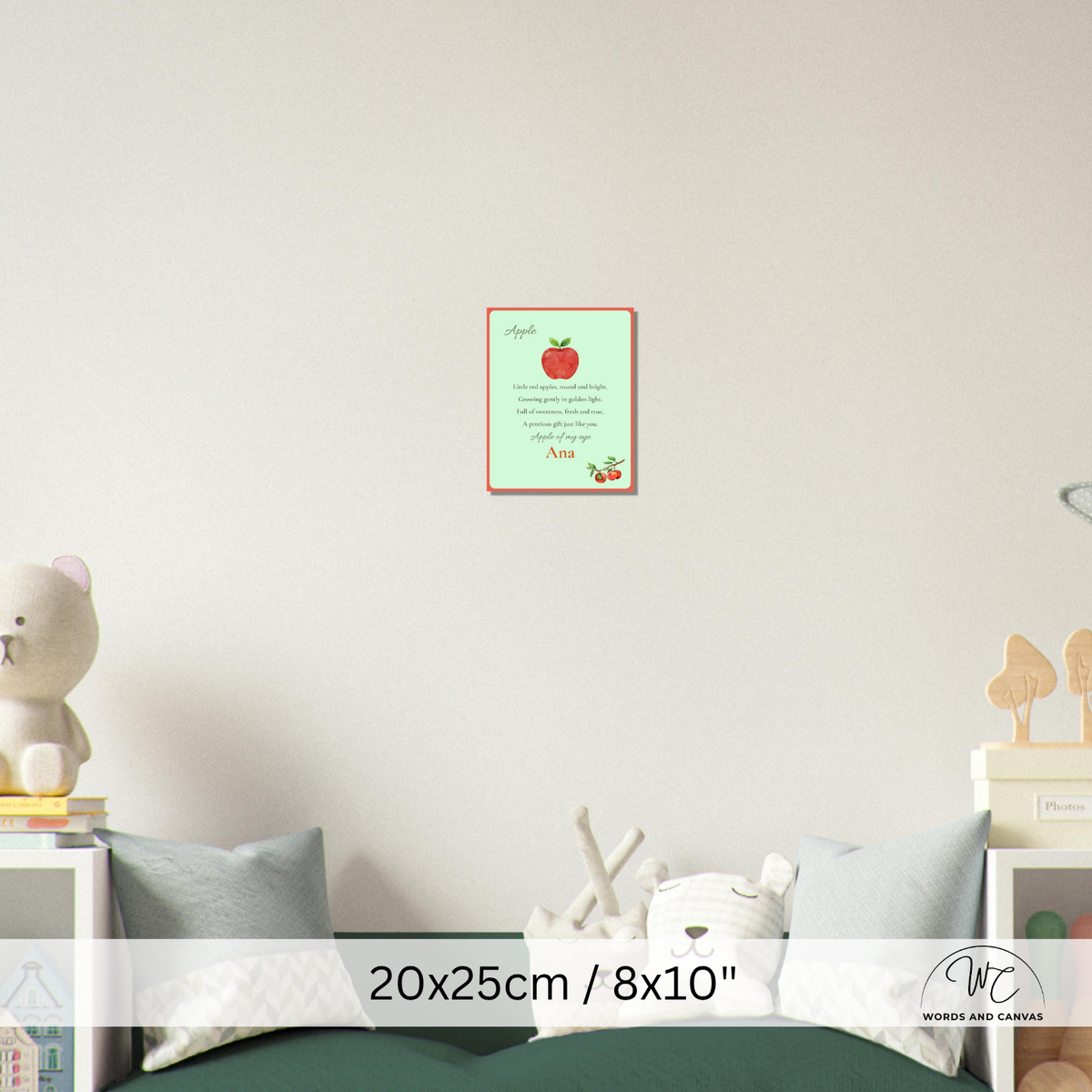 A personalized children's apple-themed wall art print displayed in a nursery setting above a bed. The print features a light green background with a red apple illustration and the name 'Ana' printed in red.