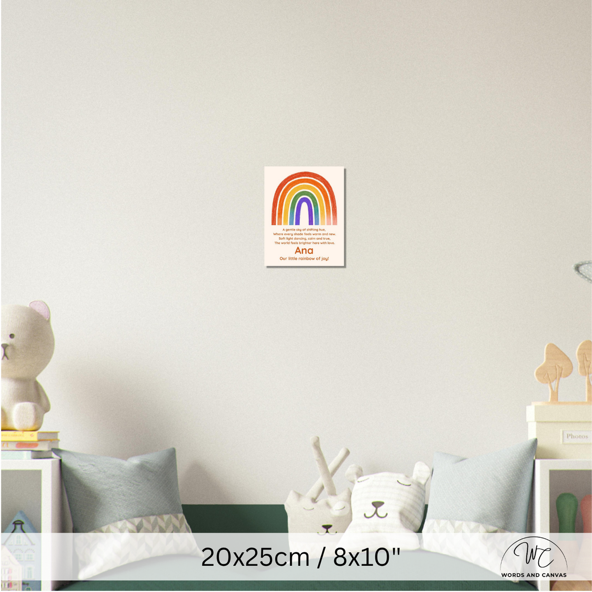A personalized children's nursery wall poster featuring a colorful rainbow and the name 'Ana' with a quote, displayed on a light gray wall above a bed with pillows and toys. The image includes a size overlay '20x25cm / 8x10"' and a brand watermark 'WORDS AND CANVAS' in the bottom right corner.