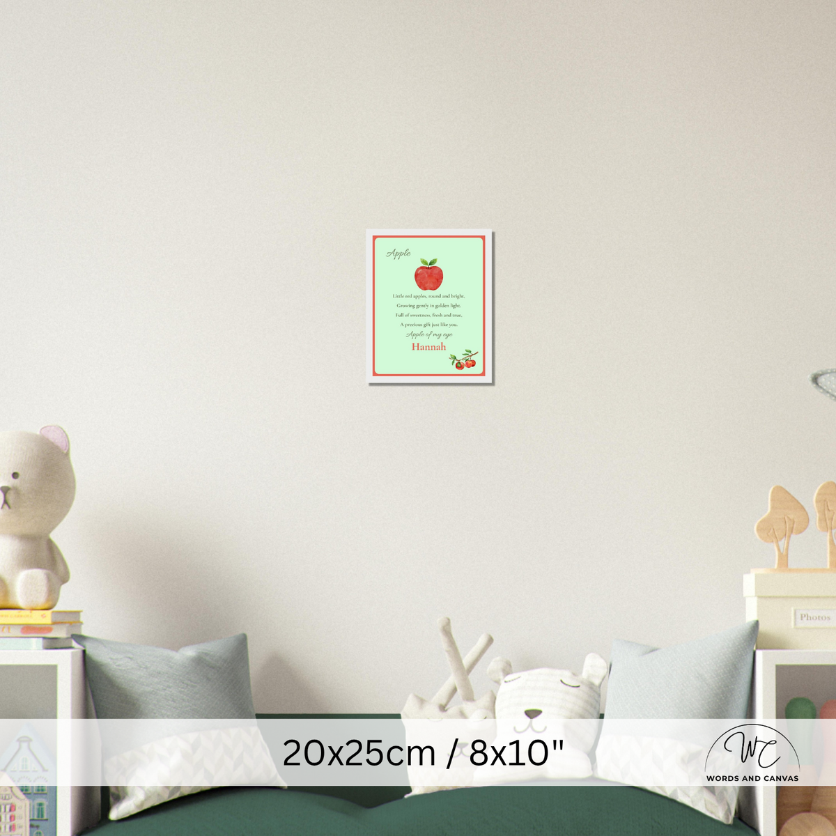 A personalized children's apple-themed wall art print displayed in a nursery setting above a bed. The print features a light green background with a red apple illustration, poem and the name 'Hannah' printed in red.