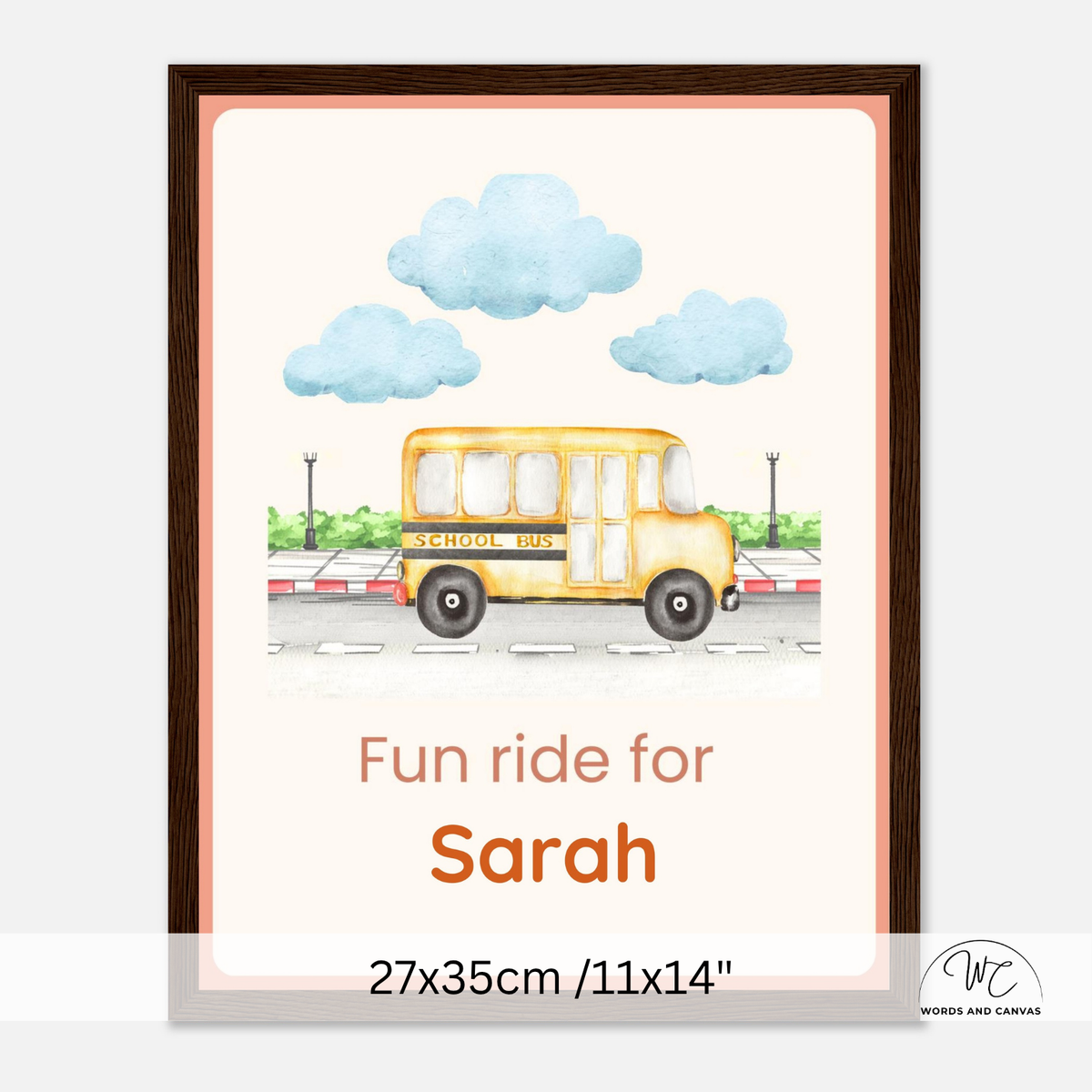 A personalized framed art print featuring a yellow school bus illustration with blue clouds and the text 'Fun ride for Sarah' and '27x35cm / 11x14"'. The print is displayed in a dark brown frame against a light gray background.