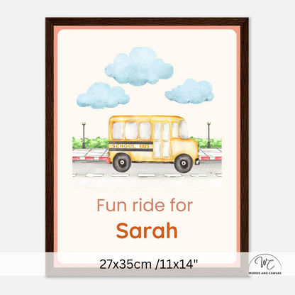 A personalized framed art print featuring a yellow school bus illustration with blue clouds and the text 'Fun ride for Sarah' and '27x35cm / 11x14"'. The print is displayed in a dark brown frame against a light gray background.