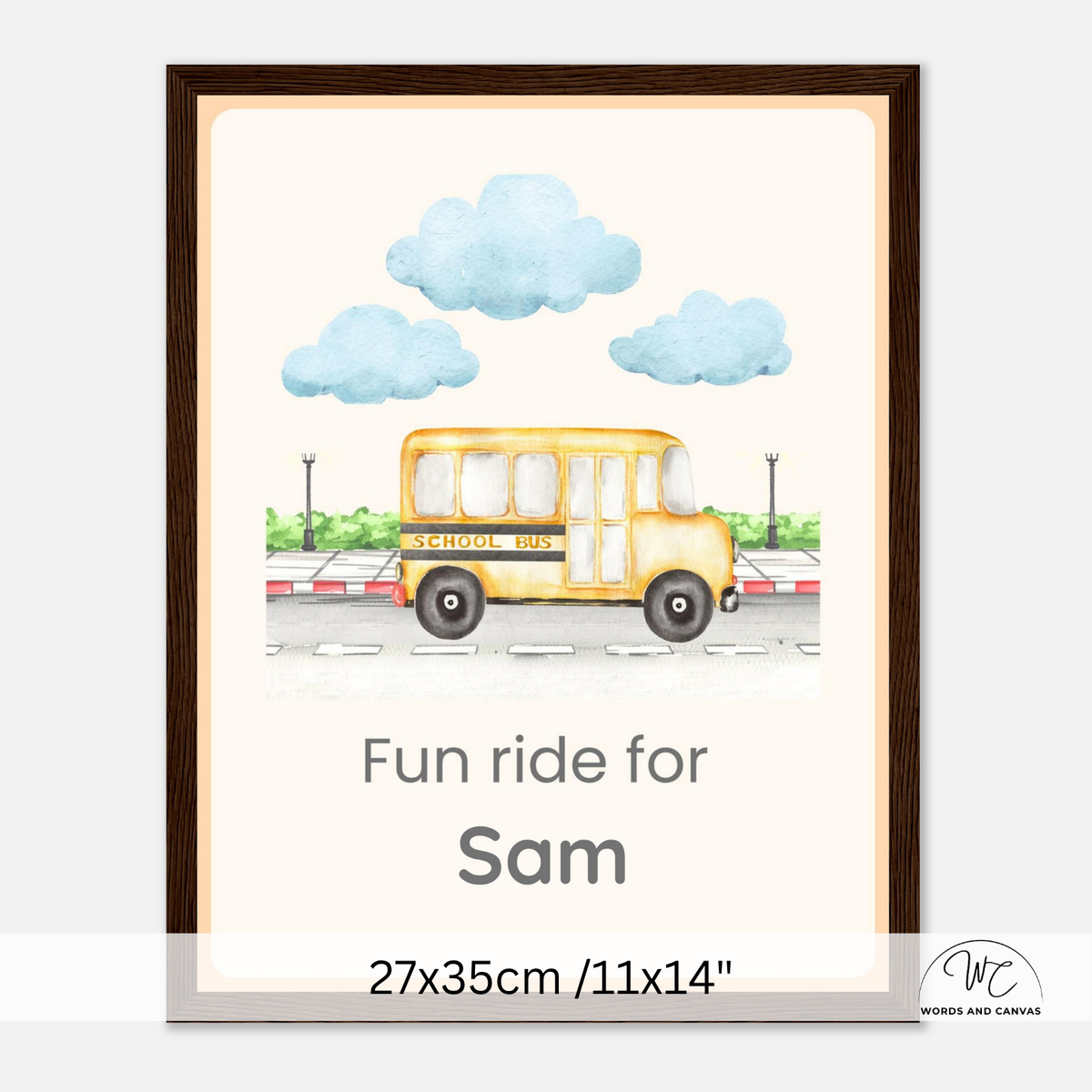 A framed personalized children's wall art print featuring a yellow school bus illustration, blue clouds, and the text 'Fun ride for Sam' with size text '27x35cm /11x14"' at the bottom. The print is shown in a dark brown frame against a light gray background.