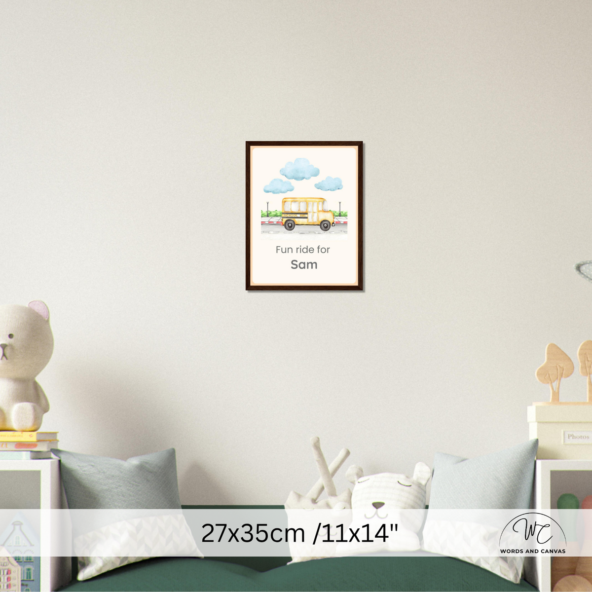 A framed personalized children's wall art print hangs on a light gray wall above a bed. The print shows a yellow school bus with blue clouds and the text 'Fun ride for Sam'.