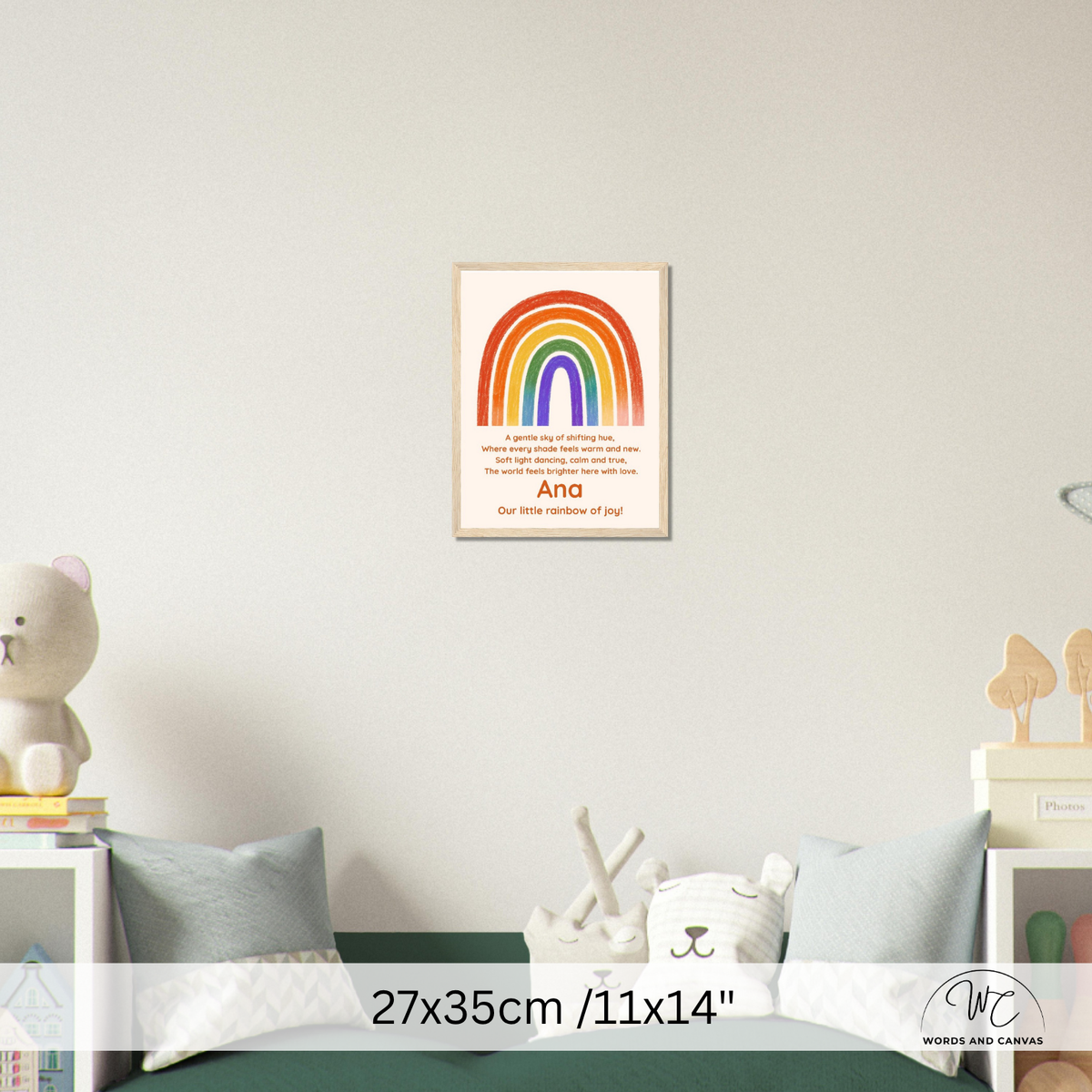 A framed personalized rainbow art print hangs on a light gray wall above a bed in a styled bedroom. The print features a colorful rainbow with the text 'I love you like this' and 'Ana Our little rainbow of joy'.
