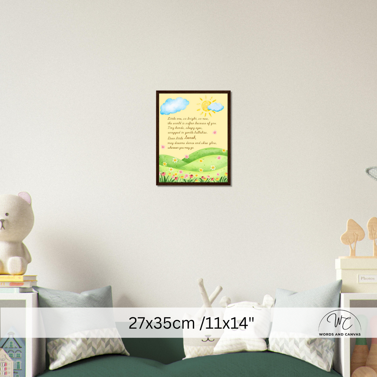 A framed wall art print featuring a whimsical landscape with blue clouds, a yellow sun, green hills, and handwritten-style text, displayed above a bed in a softly styled bedroom. A size overlay reads 27x35cm / 11x14".
