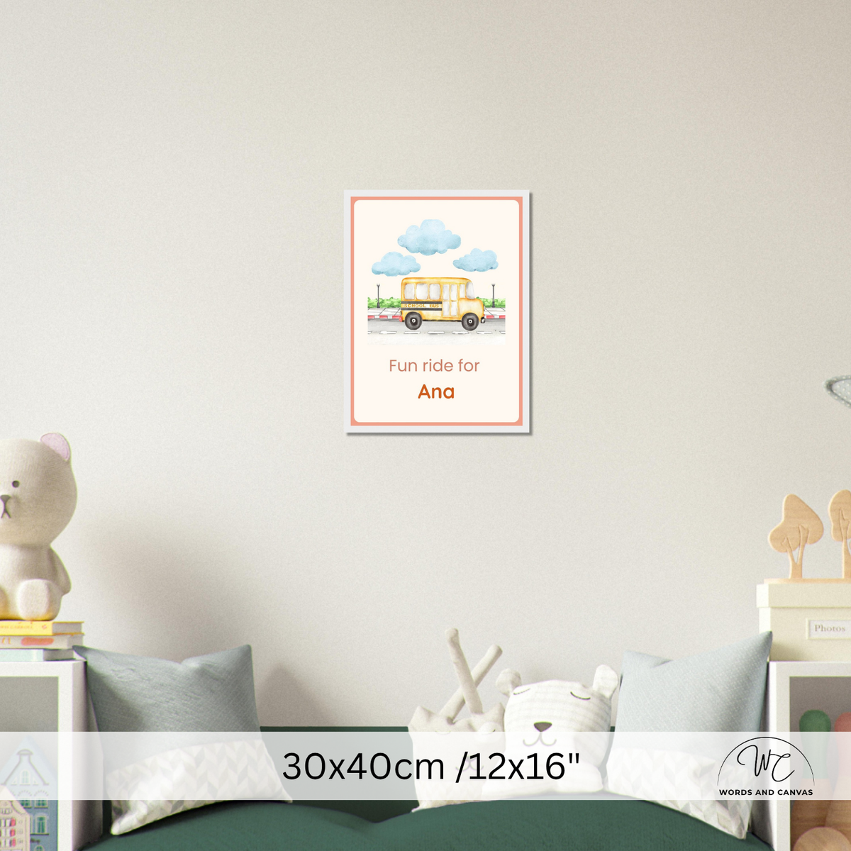A framed personalized children's wall art print hanging on a light beige wall above a bed. The print features a yellow school bus under blue clouds with the text 'Fun ride for Ana'.