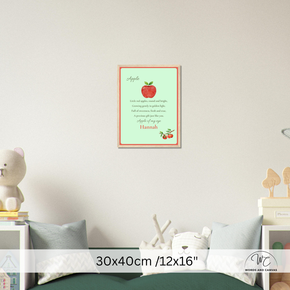 A personalized apple-themed nursery wall art print hanging on a light beige wall above a bed. The print features a light green background with a red apple illustration, a poem about apples, and the name 'Hannah' at the bottom.