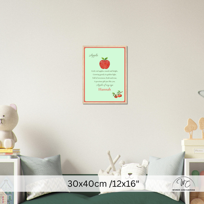 A personalized apple-themed nursery wall art print hanging on a light beige wall above a bed. The print features a light green background with a red apple illustration, a poem about apples, and the name 'Hannah' at the bottom.