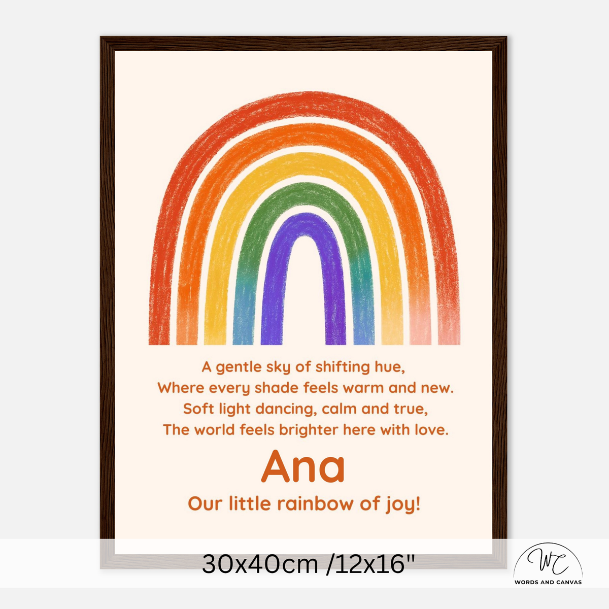 A framed personalized children's art print featuring a colorful rainbow and a poem. The print has a cream background, a hand-drawn style rainbow in red, orange, yellow, green, blue, and purple, and the name 'Ana' printed in orange.