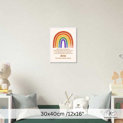 A children's nursery wall art print featuring a colorful rainbow and the words 'And our little rainbow of joy!' displayed on a light gray wall above a bed with pillows and toys. A size overlay at the bottom reads 30x40cm /12x16".