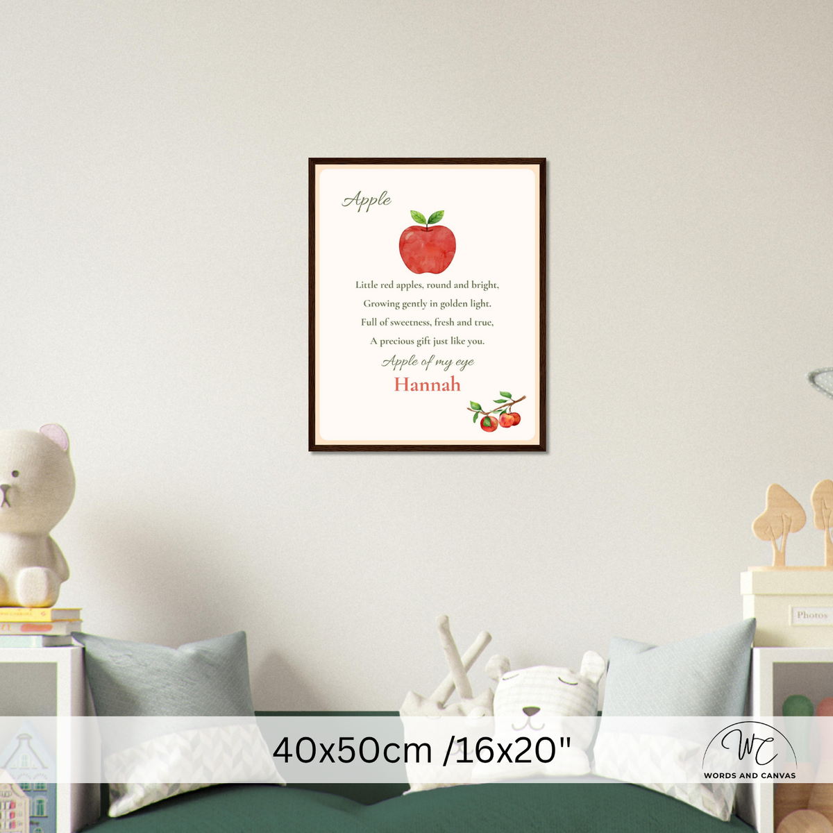 A framed personalized apple-themed nursery wall art print hanging on a light gray wall above a bed. The print features a red apple illustration, a poem about apples, and the name 'Hannah' in red script.