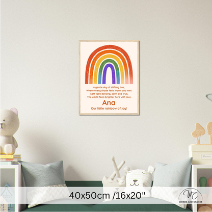 A personalized children's wall art print featuring a colorful rainbow and a poem titled 'Our little rainbow of joy' with the name 'Ana' at the bottom, displayed in a styled nursery setting above a bed.