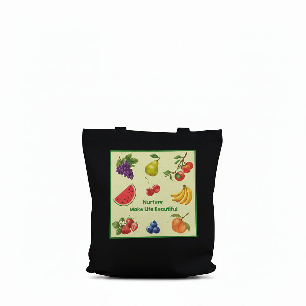 A black canvas tote bag with long shoulder straps, featuring a colorful front graphic print of various fruits (watermelon, grapes, banana, strawberries, blueberries) on a light green background with the text 'Nurture Make Life Beautiful.'.