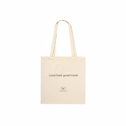 A natural canvas tote bag with two shoulder straps, featuring the printed text 'Good food, good mood' and a small circular logo near the bottom, shown against a plain white background.