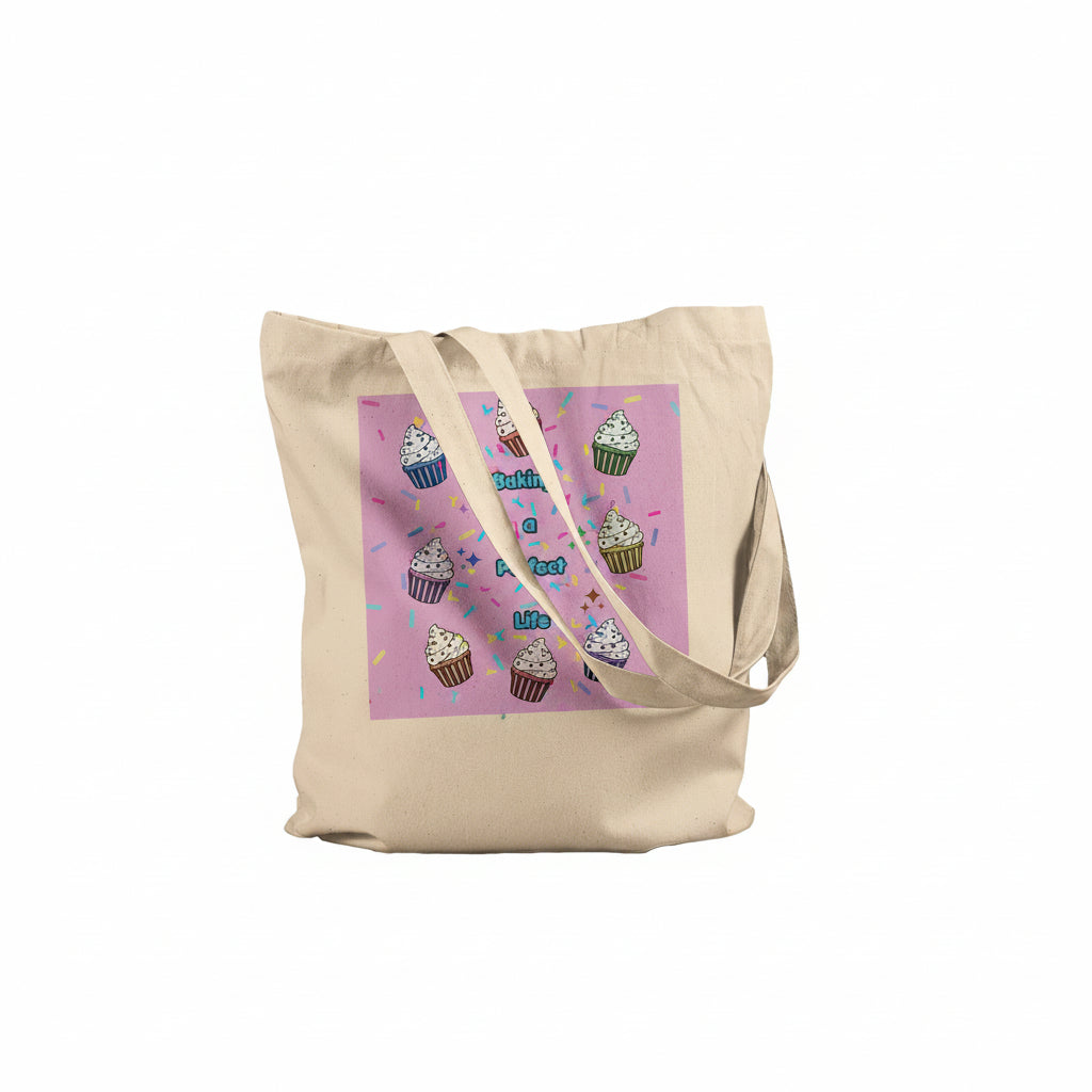A beige canvas tote bag with a pink graphic print featuring cupcakes and the text "Baking a perfect life"