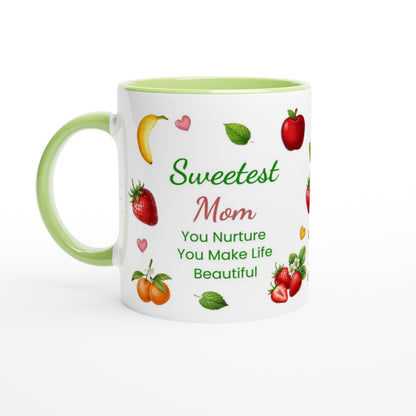 A white ceramic mug with a light green handle and interior, decorated with illustrations of fruits and the text 'Sweetest Mom You Nurture You Make Life Beautiful' on a white background.