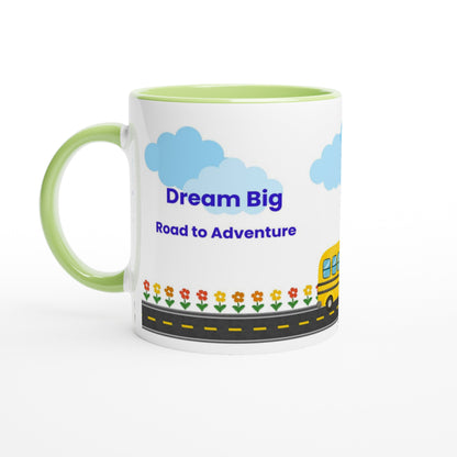 A white ceramic mug with a light green handle and interior, featuring a cartoon illustration of blue clouds, the text 'Dream Big Road to Adventures' in blue, a yellow school bus, and small flowers along a road.
