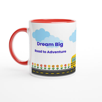 A white ceramic mug with a red interior and red handle, featuring a colorful cartoon design with blue clouds, the text 'Dream Big Road to Adventures', flowers, a road, and part of a yellow school bus.