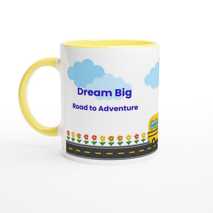 A white ceramic coffee mug with a yellow handle and yellow interior, decorated with blue clouds, the text 'Dream Big Road to Adventures' in blue, a yellow school bus, and small flowers along a road.