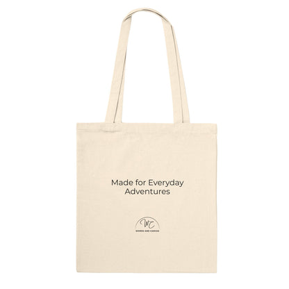 A natural canvas tote bag with black printed text and a small circular logo below