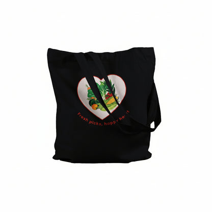 A black canvas tote bag with long shoulder straps, featuring a heart-shaped graphic on the front filled with colorful fruits and vegetables and the text 'Fresh picks, happy heart'.