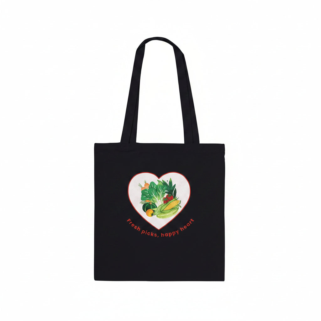 A black canvas tote bag with two shoulder straps, featuring a heart-shaped graphic on the front filled with colorful vegetables and the text 'Fresh picks, happy heart' , shown against a plain white background.