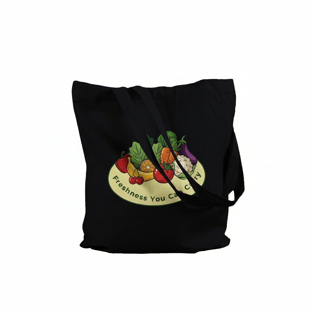 A black canvas tote bag with a colorful graphic of fresh fruits and vegetables on a yellow plate, featuring the text 'Freshness You Can Carry' on a white background.