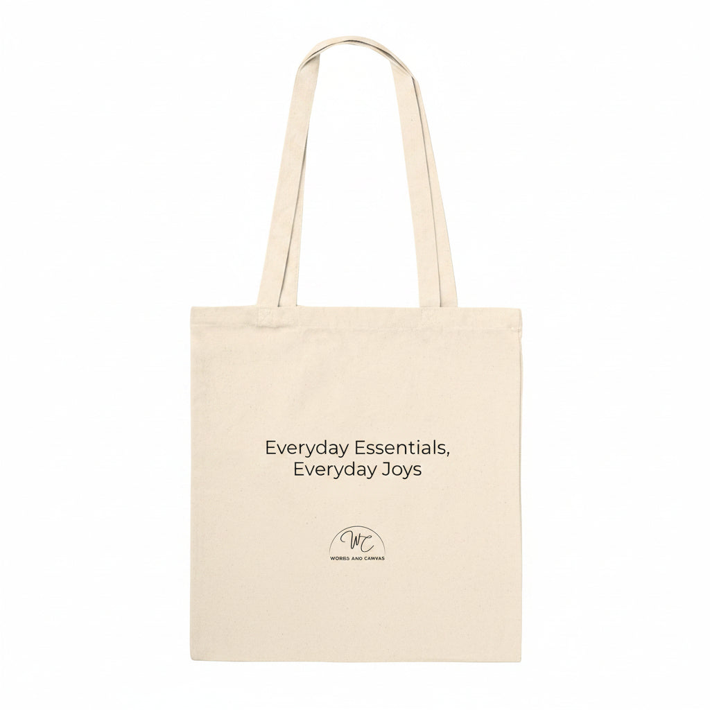A natural canvas tote bag with black printed text reading 'Everyday Essentials, Everyday Joys' and a small circular 'WC' logo below, shown on a plain white background.