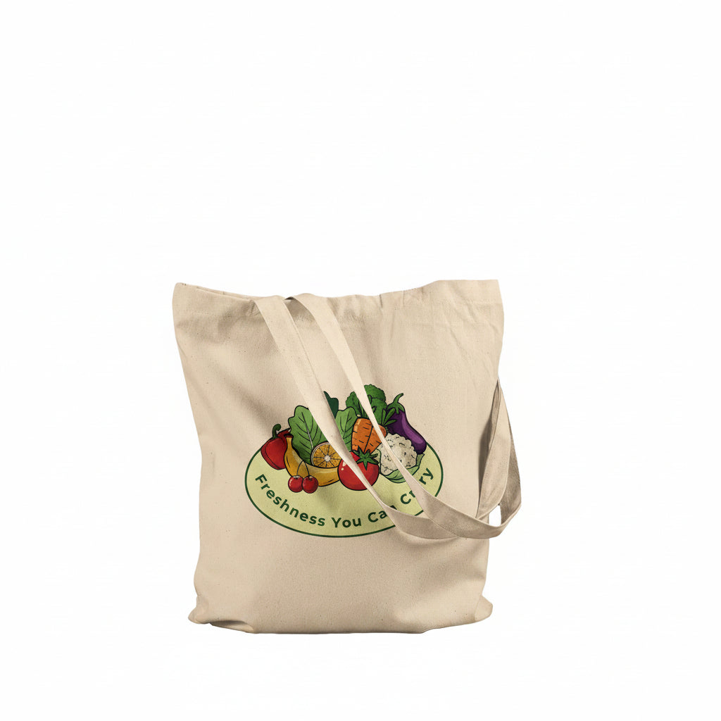 A natural beige canvas tote bag with two shoulder straps, featuring a colorful graphic of fresh vegetables on a green oval with the text 'Freshness You Can Control' printed on the front, set against a plain white background.