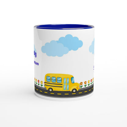 A white ceramic mug with a blue interior, featuring a cartoon illustration of a yellow school bus on a road with blue clouds and small flowers.