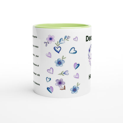 A white ceramic mug with a light green interior, decorated with purple and blue watercolor-style flowers, hearts, and text on the side, shown on a clean white background.