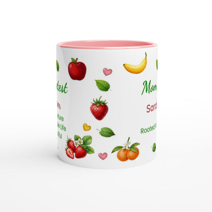 A white ceramic mug with a pink interior, decorated with illustrations of various fruits including strawberries, apples, bananas, and oranges, alongside green text on a white background.