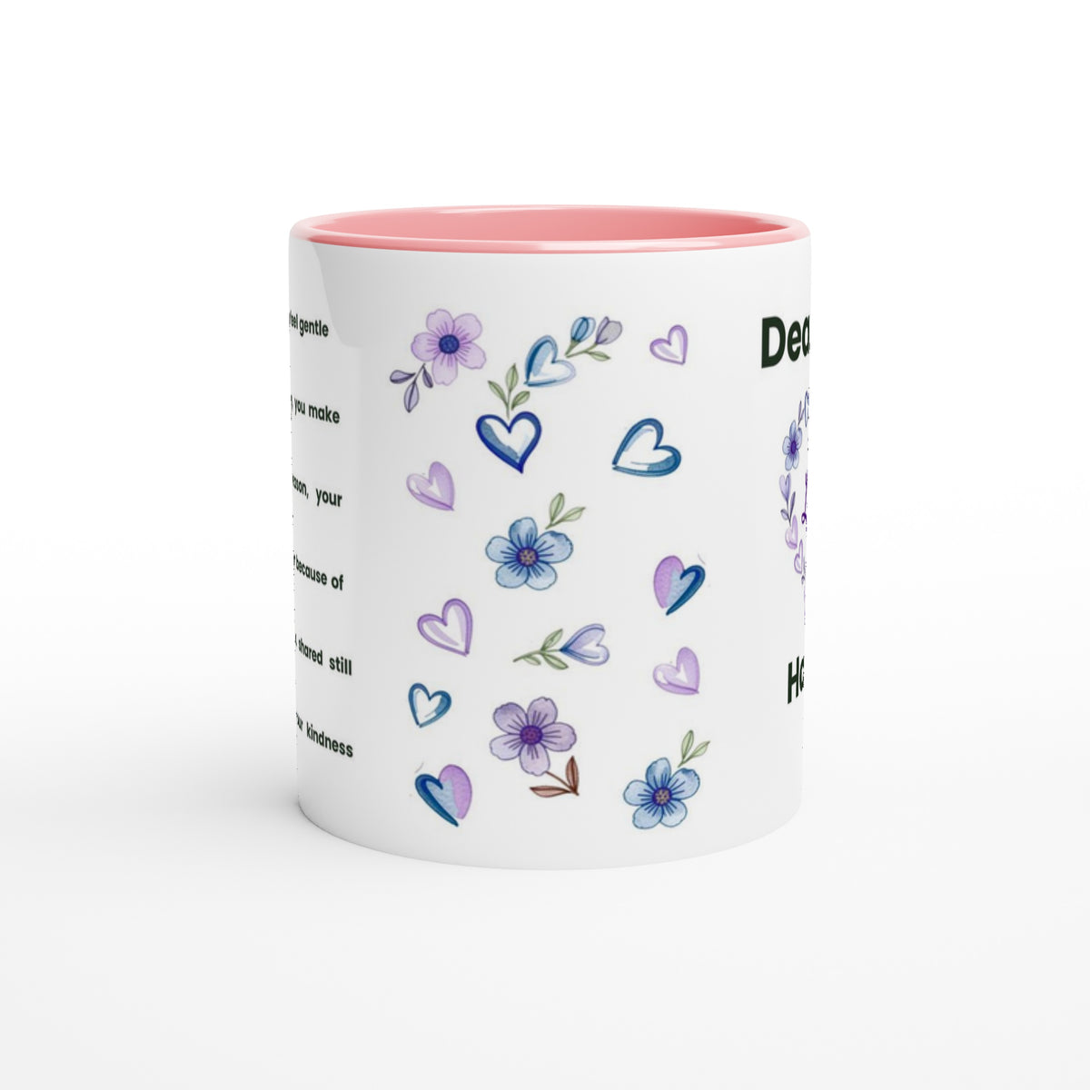 A white ceramic mug with a pink interior, decorated with purple and blue flowers, hearts, and partial black text on a clean white background.