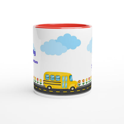 A white ceramic mug with a red interior, featuring a cartoon illustration of a yellow school bus on a road with blue clouds and small flowers.