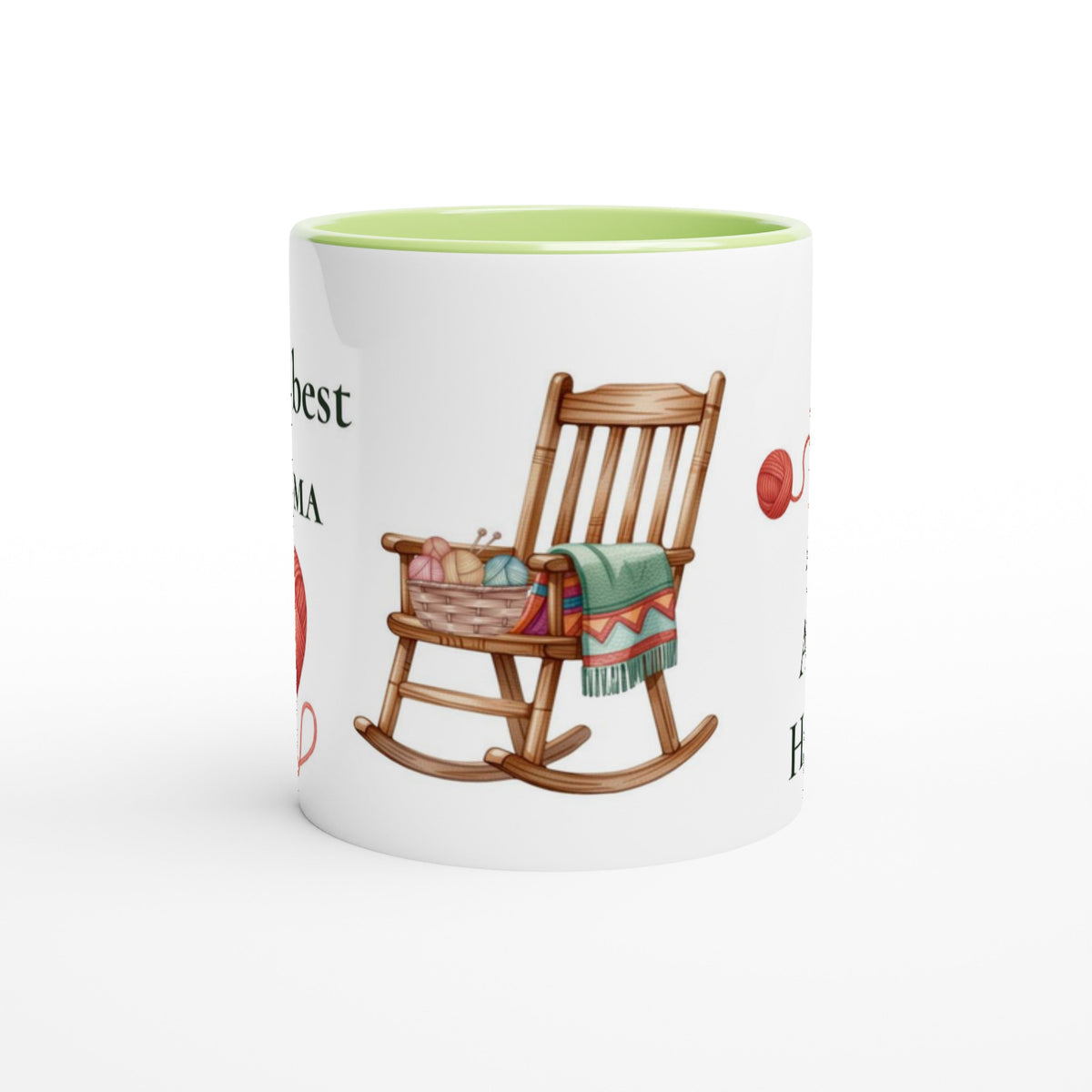 A white ceramic mug with a light green interior, featuring a printed illustration of a wooden rocking chair with a colorful knit blanket and yarn basket, alongside partial decorative text.