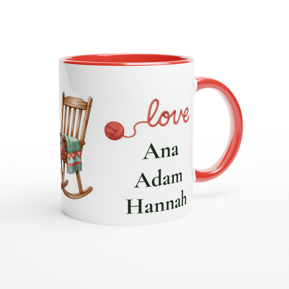 A white ceramic mug with a red interior and red handle, featuring a printed design with a wooden rocking chair, red yarn ball, the word 'love' in red script, and the names 'Ana', 'Adam', and 'Hannah' in black text.