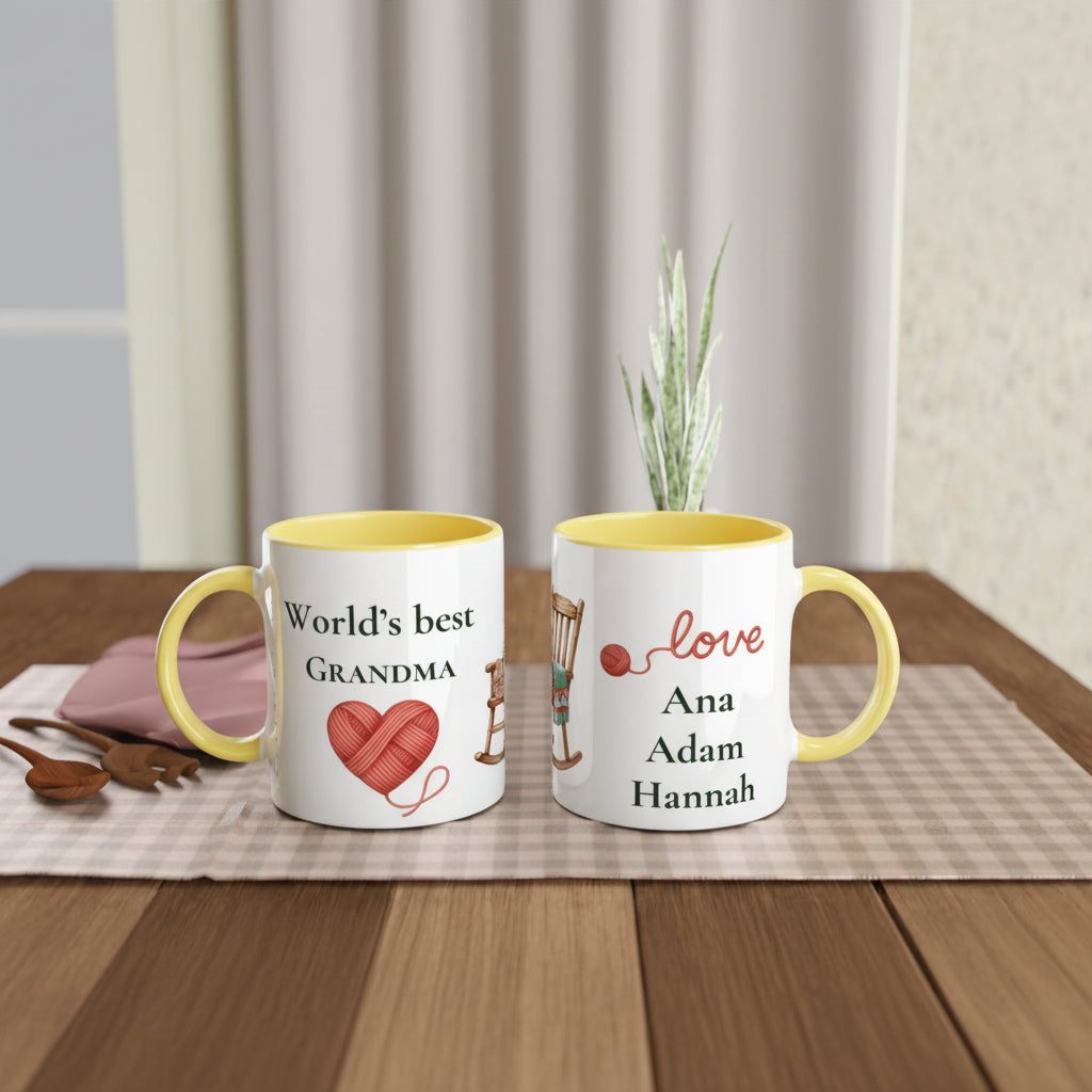 Two personalized ceramic mugs with yellow interiors and handles, displayed on a wooden table with a placemat and small plant. One mug reads 'World's best GRANDMA' with a red heart of yarn, and the other reads 'love Ana Adam Hannah
