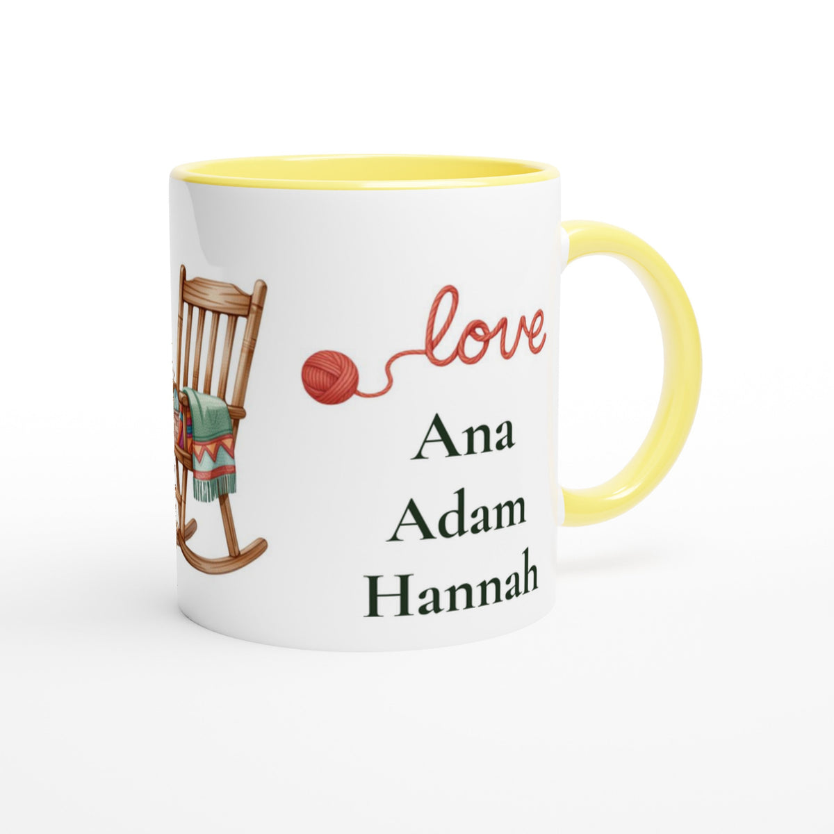 A white ceramic mug with a yellow interior and handle, featuring a printed design of a wooden rocking chair with a green blanket, a red ball of yarn, the word 'love' in red script, and the names 'Ana', 'Adam', and 'Hannah' 