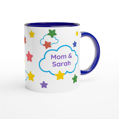 A white ceramic mug with a dark blue interior, handle, and rim, decorated with colorful stars and a blue cloud outline containing the text 'Mom & Sarah'.