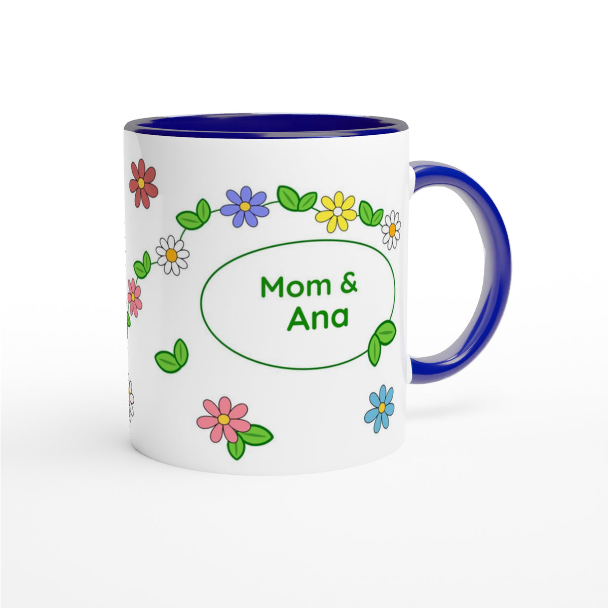 A white ceramic mug with a dark blue interior, handle, and rim, decorated with colorful cartoon flowers and a green oval frame containing the text 'Mom & Ana'.