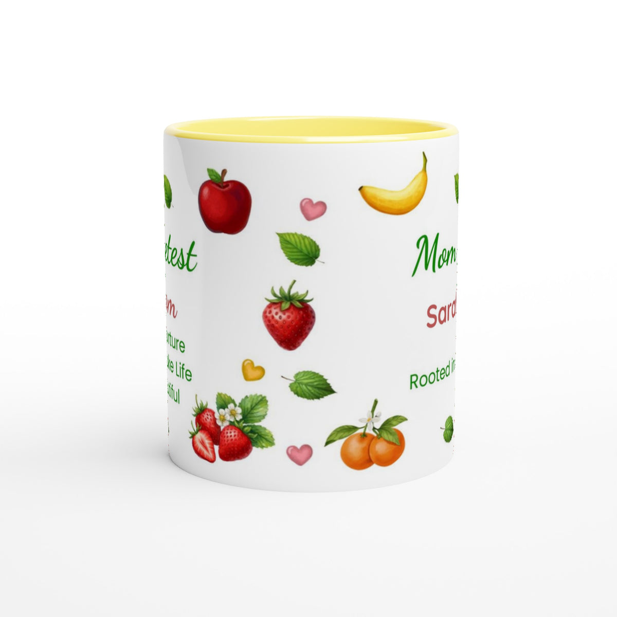 A white ceramic mug with a yellow interior, decorated with illustrations of red apples, strawberries, a yellow banana, and oranges, alongside green text and small pink hearts on a white background.
