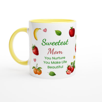 A white ceramic coffee mug with a yellow handle and yellow interior, decorated with illustrations of fruits and the text 'Sweetest Mom You Nurture You Make Life Beautiful' on a white background.