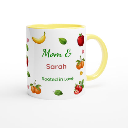 A white ceramic mug with a yellow interior and handle, decorated with illustrations of fruits and the personalized text 'Mom & Sarah Rooted in Love'.
