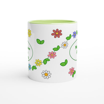 A white ceramic mug with a light green interior, decorated with a colorful pattern of cartoon-style flowers and green leaves.
